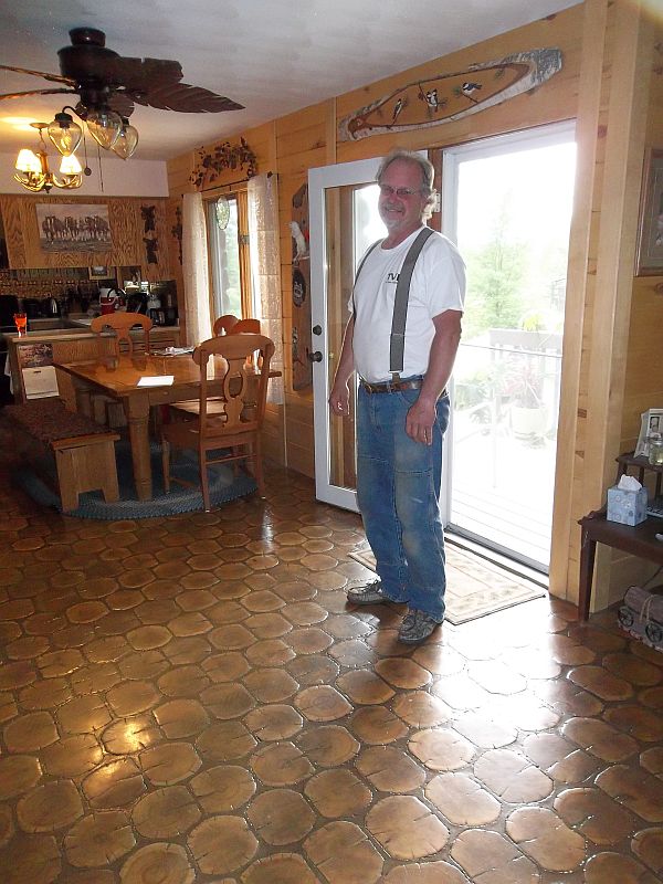 Steve, the craftsman, stands proudly on his cordwood floor.